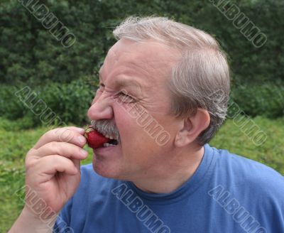Elderly man, eating a strawberry