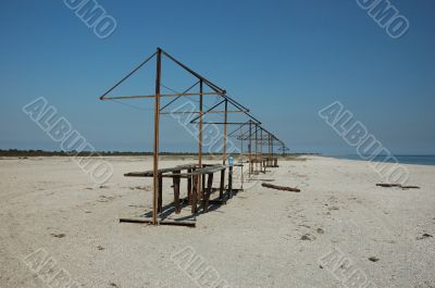 Wild or abandoned beach with old rusty sunshades
