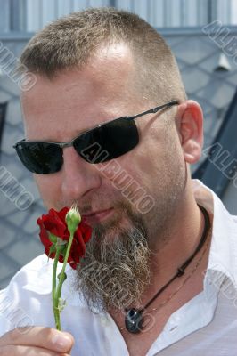 Young man with a red rose and sunglasses.