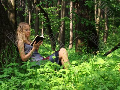 Girl, reading a book in a forest