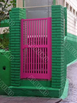 Pink door on a green fence