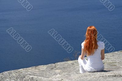 Red-haired girl looking over blue water