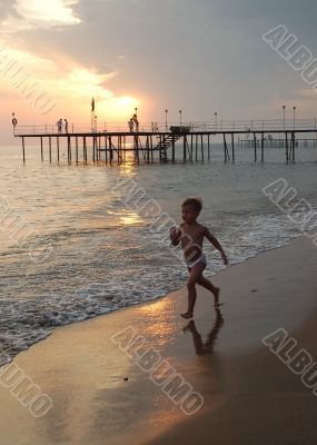 happy young boy running on the beach at sunset 2