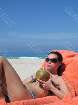 girl on the beach drinking out of a coconut
