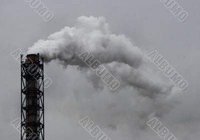Smoking industrial pipe on gray sky