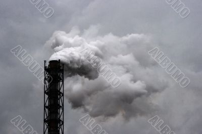 Smoking industrial pipe on gray sky
