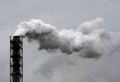 Smoking industrial pipe on gray sky