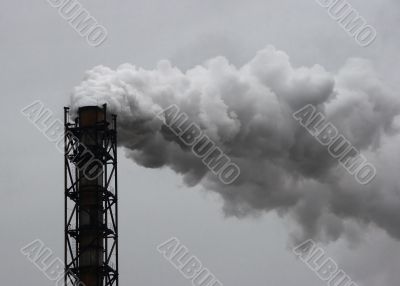 Smoking industrial pipe on gray sky