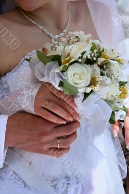 hands of newlyweds with bouquet
