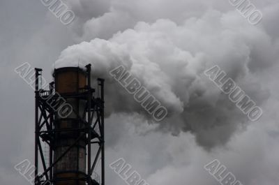 Smoking industrial pipe on gray sky