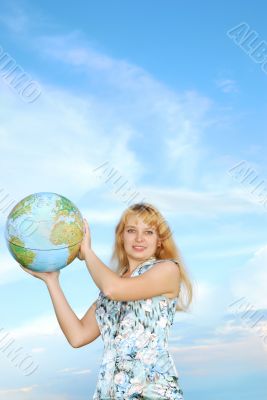 blonde in field on green grass holding globe in hand under blue