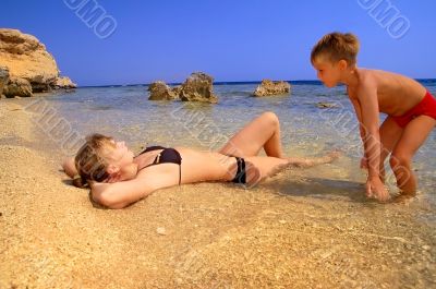 ma and son on beach on background blue sky