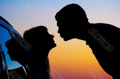 two Silhouettes of kissing people on sunset background