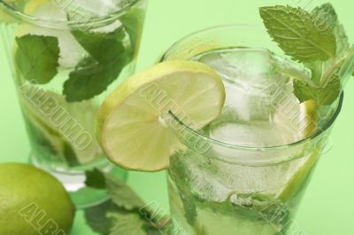 Two mojito cocktails on green background