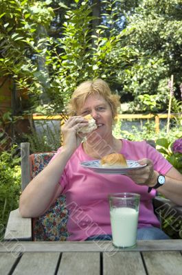 elderly woman is eating lunch in the garden