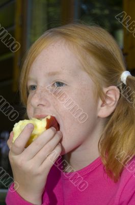 little girl is eating an apple