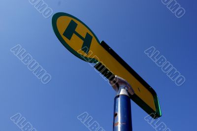 Sign a bus stop in front of blue sky.
