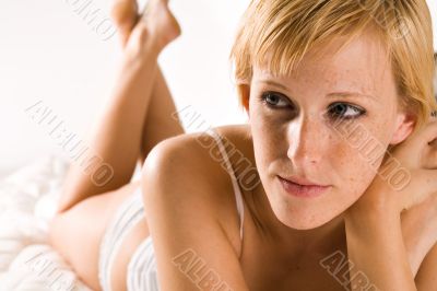 Blond in lingerie resting on her bed
