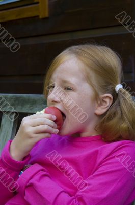 little girl is eating an apple