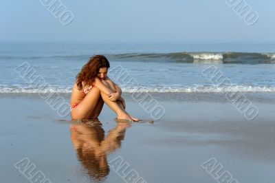 Beautiful girl sitting on the ocean beach