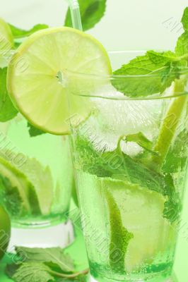 Two mojito cocktails on green background