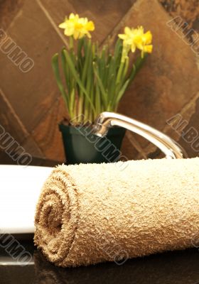 Rolled up towel and flowers in the bathroom