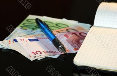Money, notebook and pencil