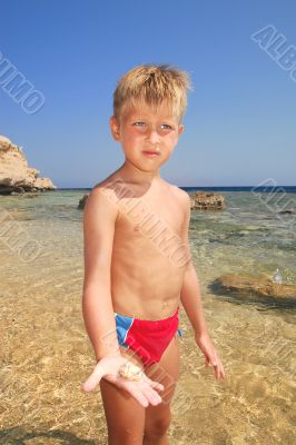 beach boy shows stone or seashell