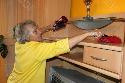 Old woman cleans a cupboard