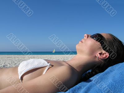 girl with sunglasses tanning on the beach