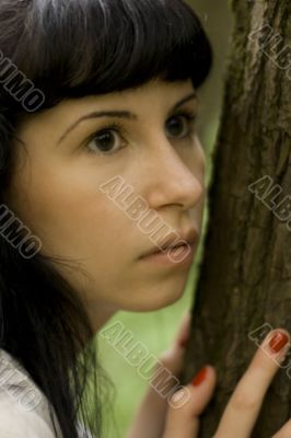 girl hiding behind a tree