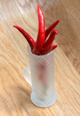 red peppers in a frosted glass on wood table