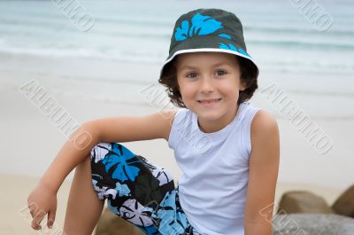 Pretty boy sitting on the stone from the beach