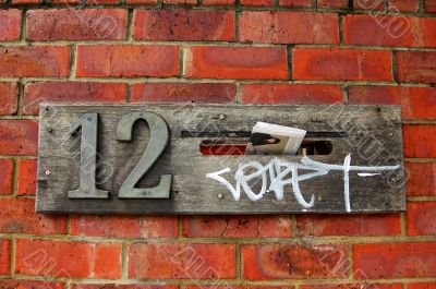 Mail box on red brick wall covered with graffiti
