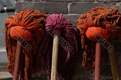 Three colored mops next to each other at the wall