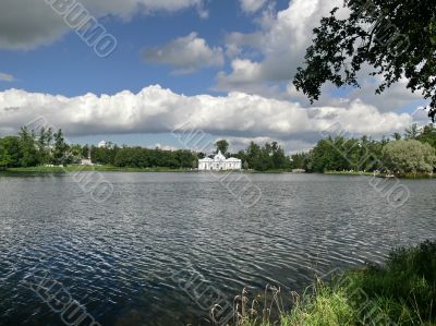House on pond. White clouds on blue sky.