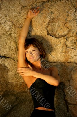 Sexy photo of a young woman in front of a rock.