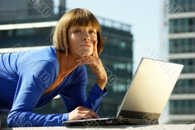 Young woman with a laptop in a blue dress.