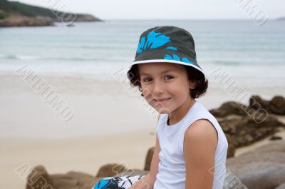Pretty boy sitting on the stone from the beach