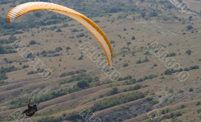 Orange paraglider above the valley