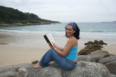 Young woman reading sitting on the beach