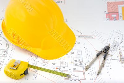 Building plan with safety helmet, pair of compasses and rolling