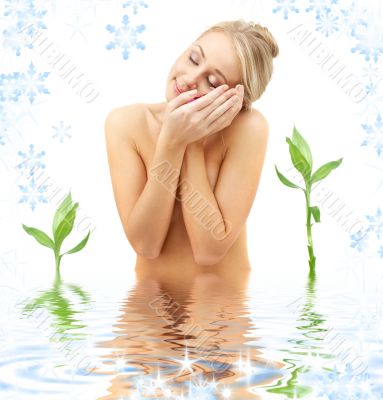 happy blonde with flower petals and green plants in spa