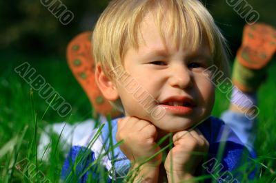 Child lays on a green grass