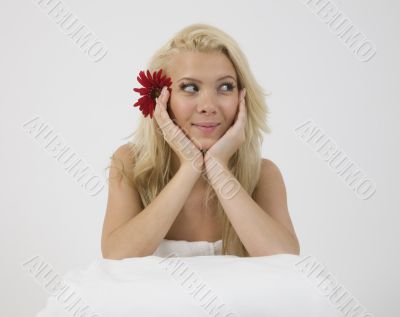 smiling face of model with red gerbera in hair