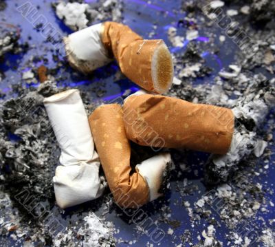 Four smoked cigarettes in a dirty ashtray