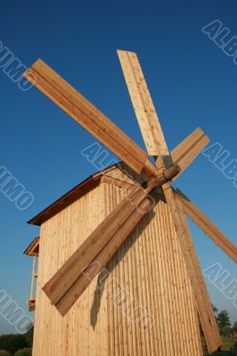 Rural wooden windmill against blue sky