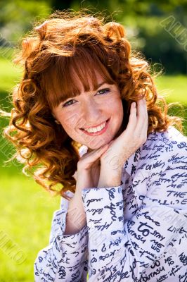 Bright portrait of red-haired young woman outdoors