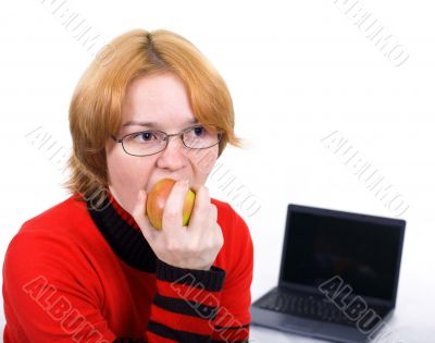 The woman bites an apple against the laptop