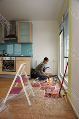Young woman paints a wall in the kitchen